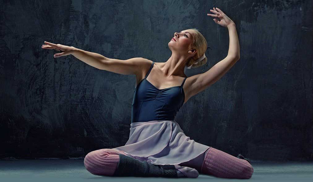 Dancer in bodusuit and wrap skirt in pose on the floor